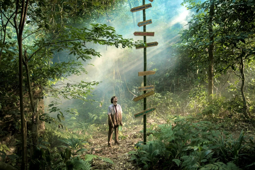 A man stares at a signpost in the jungle looking in awe at the number of options available.